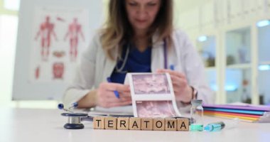 Tıbbi masadaki tahta bloklar şırınganın yanındaki Teratoma kelimesini heceliyor. Kadın doktor doku taraması yapıyor. Tümör teşhisini tamamlayan resimler.