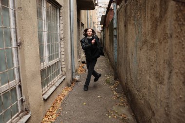 Gençler dar bir sokakta mutlu adımlarla yürürler. Etrafı boyalı, eski binalarla çevrilidir. Düşen yapraklar yere saçılır ve sonbahar atmosferini artırır..