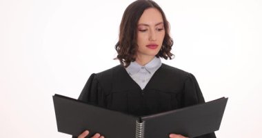 Dava dosyasını okurken siyah cüppeli kadın yargıç elinde dosya tutuyor. Ciddi hakimlik çalışmaları belge sayfaları önemli kararı yavaş çekimde hazırlıyor