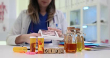 Kadın doktor ultrason görüntülerini dikkatlice inceler. Tahta küplerin kısaltması SIBO açıkça hastanın bağırsak teşhisini gösterir.