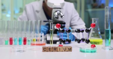 Laboratuvar çalışanları yüksek hassasiyetli mikroskop altında numune hazırladı. Tahta küpler test tüplerinde analiz edilen elementi gösteren kelime seryumunu oluşturur.