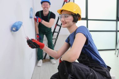 Aydınlık, havadar bir odada, iki arkadaş eğlenceli bir hafta sonunun tadını çıkarıyorlar. Duvarlara renkli boya ekliyorlar. Biri resim yaparken gülümserken, diğeri mutlu bir şekilde yardım ediyor, neşeli bir atmosfer yaratıyor..