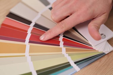 Bir el, parlak, havadar bir tasarım uzayındaki ilham ve yaratıcılık sürecini yansıtan renk örneklerinden nazikçe seçer..