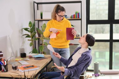 İki kadın renkli kırtasiyelerle dolu şık bir çalışma alanında iş birliği yapıyor. Biri fikirlerini paylaşırken, diğeri takım çalışmasını ve yaratıcılığı eylemde yansıtıyor..