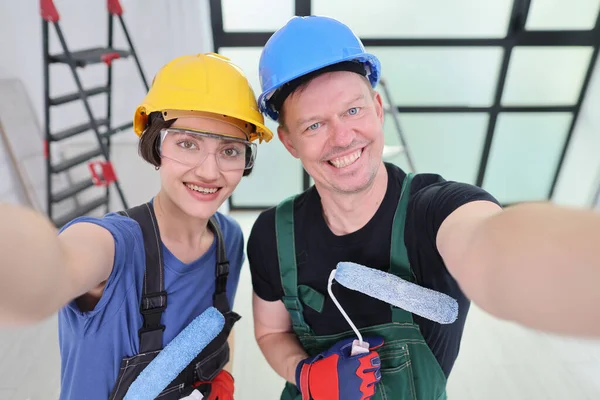 İki hevesli ressam yeni boyanmış bir odada gülümseyerek poz veriyor. Koruyucu giysiler giyerek, sanatsal dokunuşlarıyla taze ve canlı alanı geliştirmeye hazırlanıyorlar..