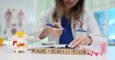 Tablet ve omurgalar arası diskin anatomik modelinin yanında tahta bloklar halinde Radikülit yazılır. Doktor detaylı tedavi planı yazıyor.