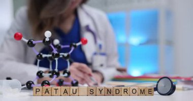 Tahta küpler, masadaki molekül modelinin yanında Patau Sendromu anlamına geliyor. Genetik doktor üç aşamalı hastalık riskini açıklayan bir rapor yazdı.