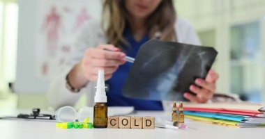 Tahta küpler kelimeyi soğuk diye heceler. Doktor kadın hasta randevusu için ilaç ve damlatıcıyla göğüs röntgeni üzerinde çalışıyor.