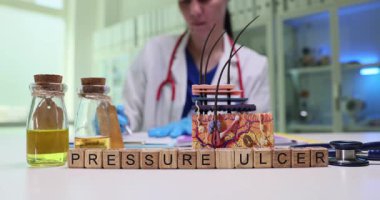 Tahta küpler, deri modelinin yanında basınç ülseri anlamına gelir. Doktor kadın, klinikte yara bakımı ve kronik yara önleme hakkında notlar üzerinde çalışıyor.