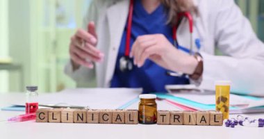 Tahta küplerin tıbbi belgelerin yanında klinik deney ifadesi var. Kadın doktor klinikteki araştırma oturumu için protokol yazma notlarını kontrol ediyor