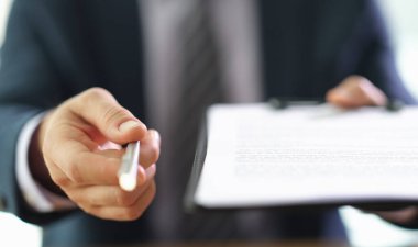 Modern ofis ortamında, iyi giyimli bir adam görülmemiş bir izleyiciye bir belge sunar. Kendinden emin el hareketleri paylaştığı bilginin önemini gösteriyor..