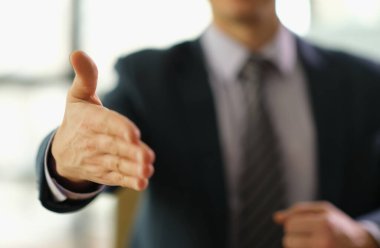 Kendine güvenen bir birey şık bir ofis alanında el sıkışmak için elini uzatarak öğleden sonra güneş ışığı sırasında yeni bir iş ilişkisinin başlangıcını simgeler..
