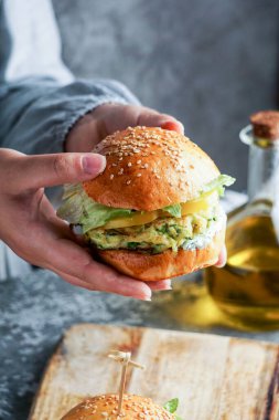 Kadınların elinde salata ve yoğurt soslu vejetaryen mercimek hamburgerleri. Bitki temelli gıda konsepti.