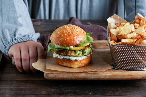 Kadınların elinde salata ve yoğurt soslu vejetaryen mercimek hamburgerleri. Bitki temelli gıda konsepti.