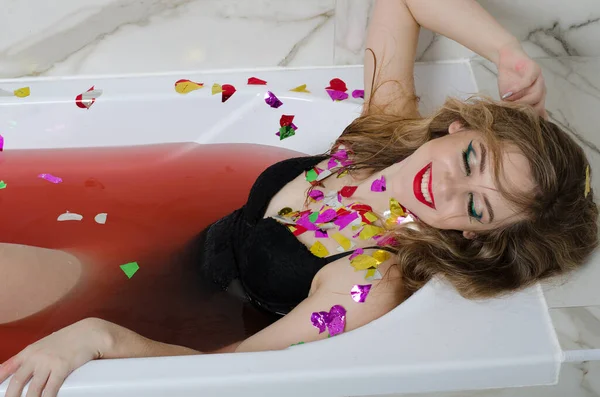 赤い水のお風呂で明るいメイクの女の子 — ストック写真