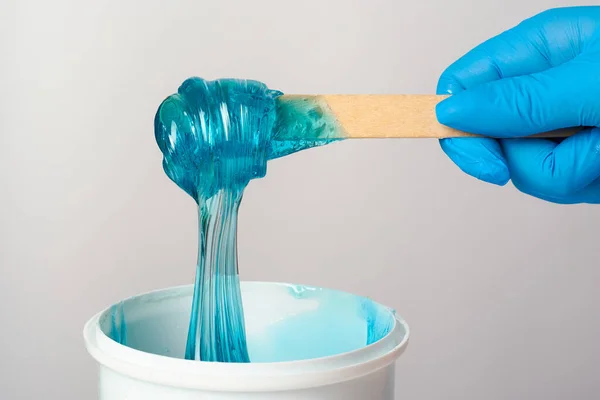 Pasta de azúcar azul líquido o cera depilatoria en un palo de madera de cerca sobre un fondo blanco. — Foto de Stock