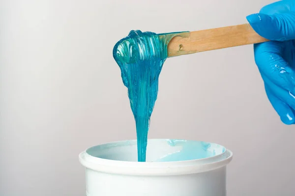 Liquid blue sugar paste or depilatory wax on a wooden stick close up on a white background. — Fotografia de Stock