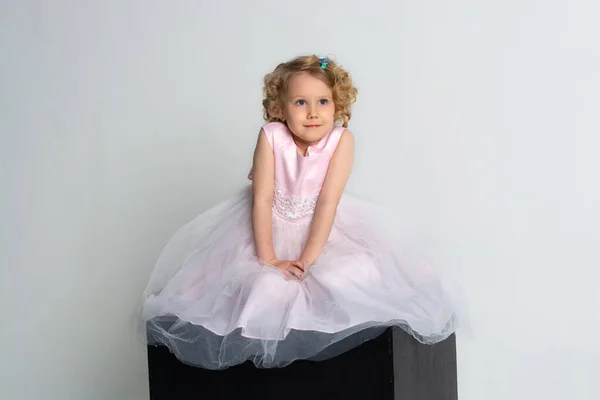 Una Niña Vestido Rosa Corona Sienta Cubo Negro Sobre Fondo —  Fotos de Stock
