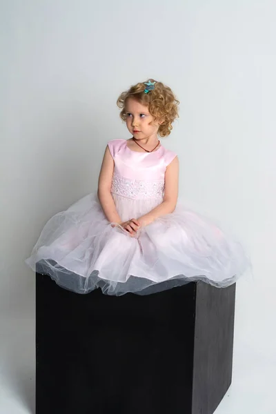 Mała Dziewczynka Różowej Sukience Koronie Siedzi Czarnej Kostce Białym Tle — Zdjęcie stockowe