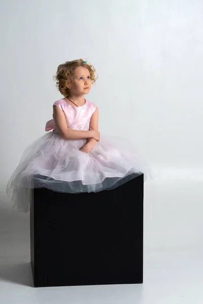 Mała Dziewczynka Różowej Sukience Koronie Siedzi Czarnej Kostce Białym Tle — Zdjęcie stockowe