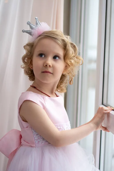 Mała Dziewczynka Różowej Sukience Korona Uśmiecha Się Przy Oknie — Zdjęcie stockowe