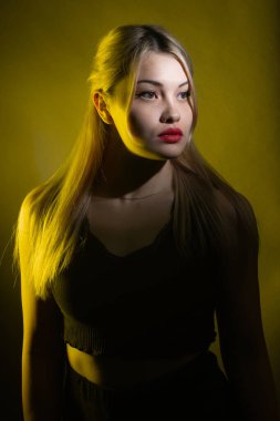 Sarı ışıkta parlak makyajlı sarışın bir kızın portresi..