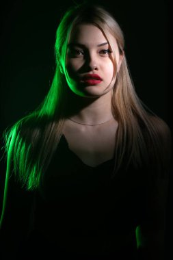 Yeşil ışıkta parlak makyajlı sarışın bir kızın portresi..