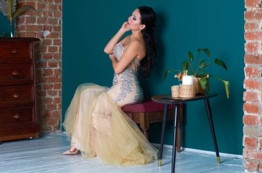 Turkuaz duvarlı bir odada şık beyaz elbiseli güzel bir kız.