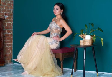 Turkuaz duvarlı bir odada şık beyaz elbiseli güzel bir kız.