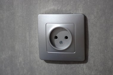 Gri beton duvarda gri bir elektrik prizi