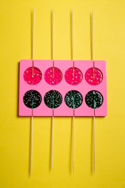 Sarı arka planda yemek pişirmek için tek bir çubuk üzerinde lolipoplar.
