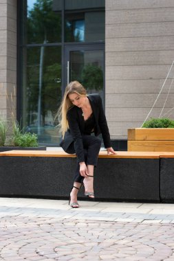 Şehirde siyah takım elbiseli sarışın bir kadın. Yürüyüş yapan bir iş kadını.