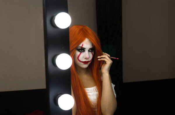 a girl in a clown costume to apply makeup