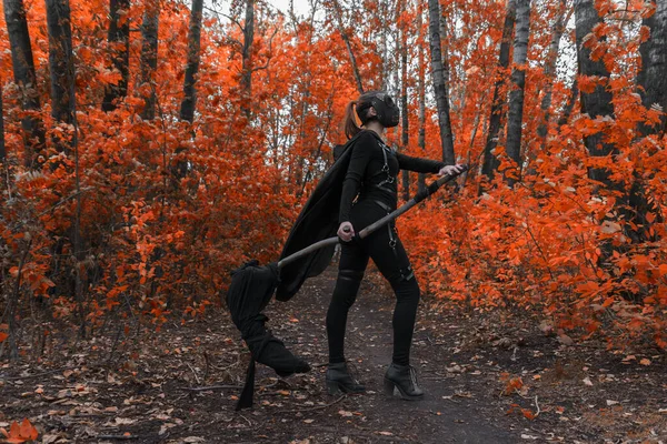 Uma menina em um traje bdsm e uma máscara preta em uma forest.an vermelho ideia para halloween. — Fotografia de Stock