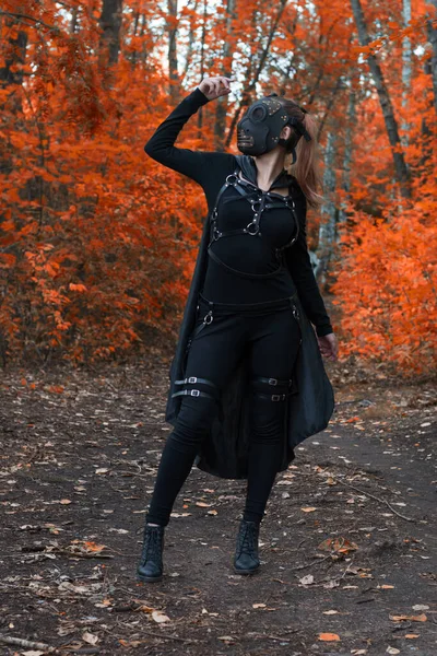 Uma menina em um traje bdsm e uma máscara preta em uma forest.an vermelho ideia para halloween. — Fotografia de Stock