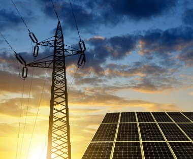 Güneş panelleri ile elektrik pilon gün batımında.