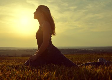 genç kadın bir çayır on gün batımında germe