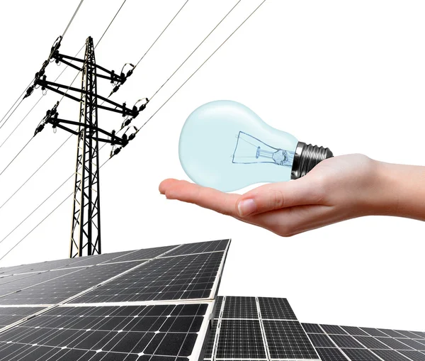 Hand innehav glödlampa. I bakgrunden solpanelen och högspänning tower. — Stockfoto