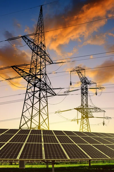 Solar panels with electricity pylons at sunset. — Stock Photo, Image