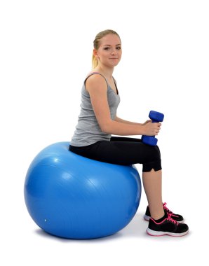 Topun üstüne oturan dumbbells ile kız