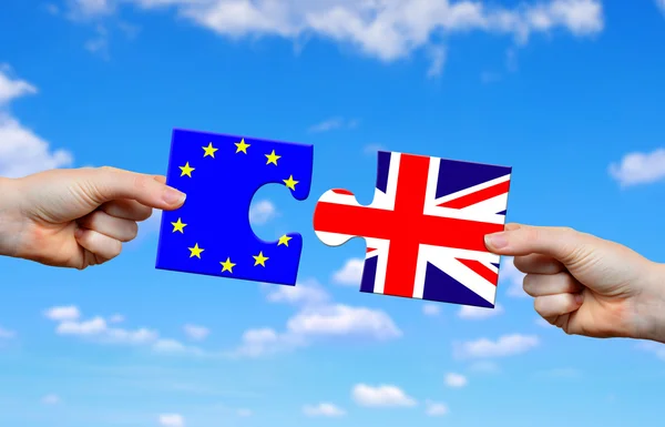 Mani in mano puzzle con bandiera del Regno Unito e dell'UE . — Foto Stock
