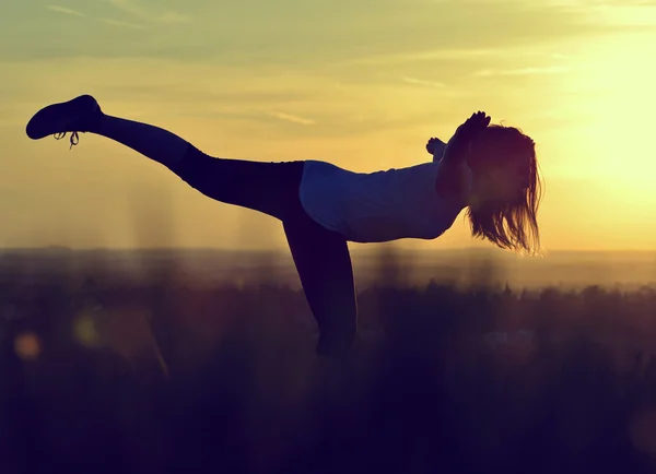Silhouette of young woman stretching — Stock Photo, Image