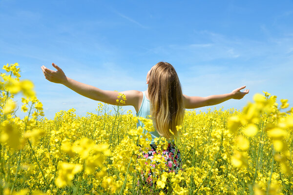 Young happy woman on blooming rapeseed field