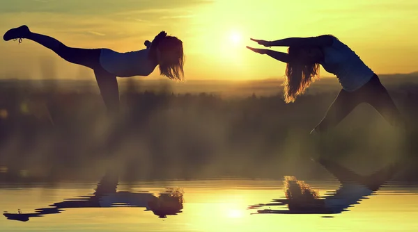 Silhouette girls stretching on a meadow — Stock Photo, Image
