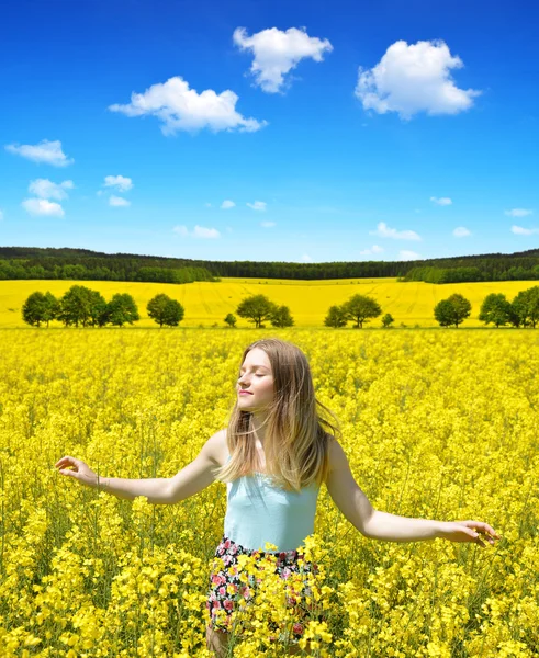 Young happy woman on blooming rapeseed field — Stock Photo, Image