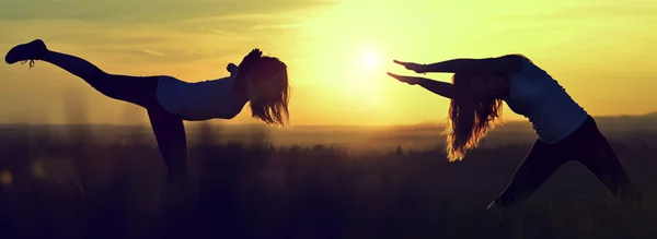 Silhouette girls stretching on a meadow — Stock Photo, Image
