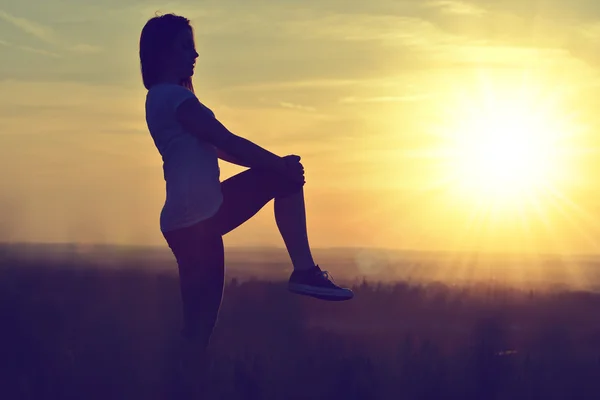 Silhouette of young woman stretching — Stock Photo, Image