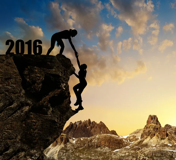 Silhouette flickor klättrar in i nytt år 2016. — Stockfoto