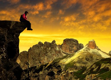 Sexten Dolomites günbatımında bir kayaya oturan kız
