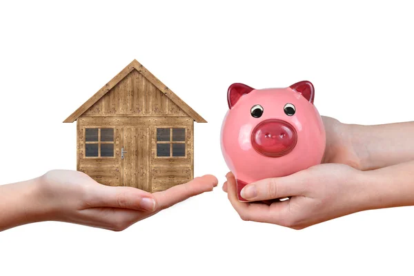 Hands holding wooden house and pink piggy bank — Stock Photo, Image